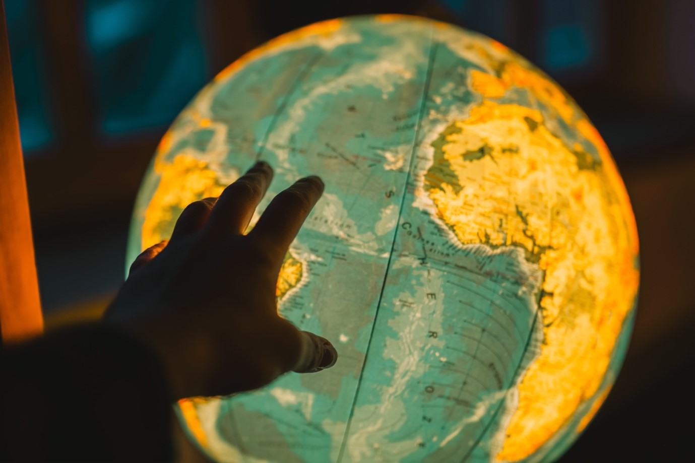 a hand on an illuminated globe depicting a worldview