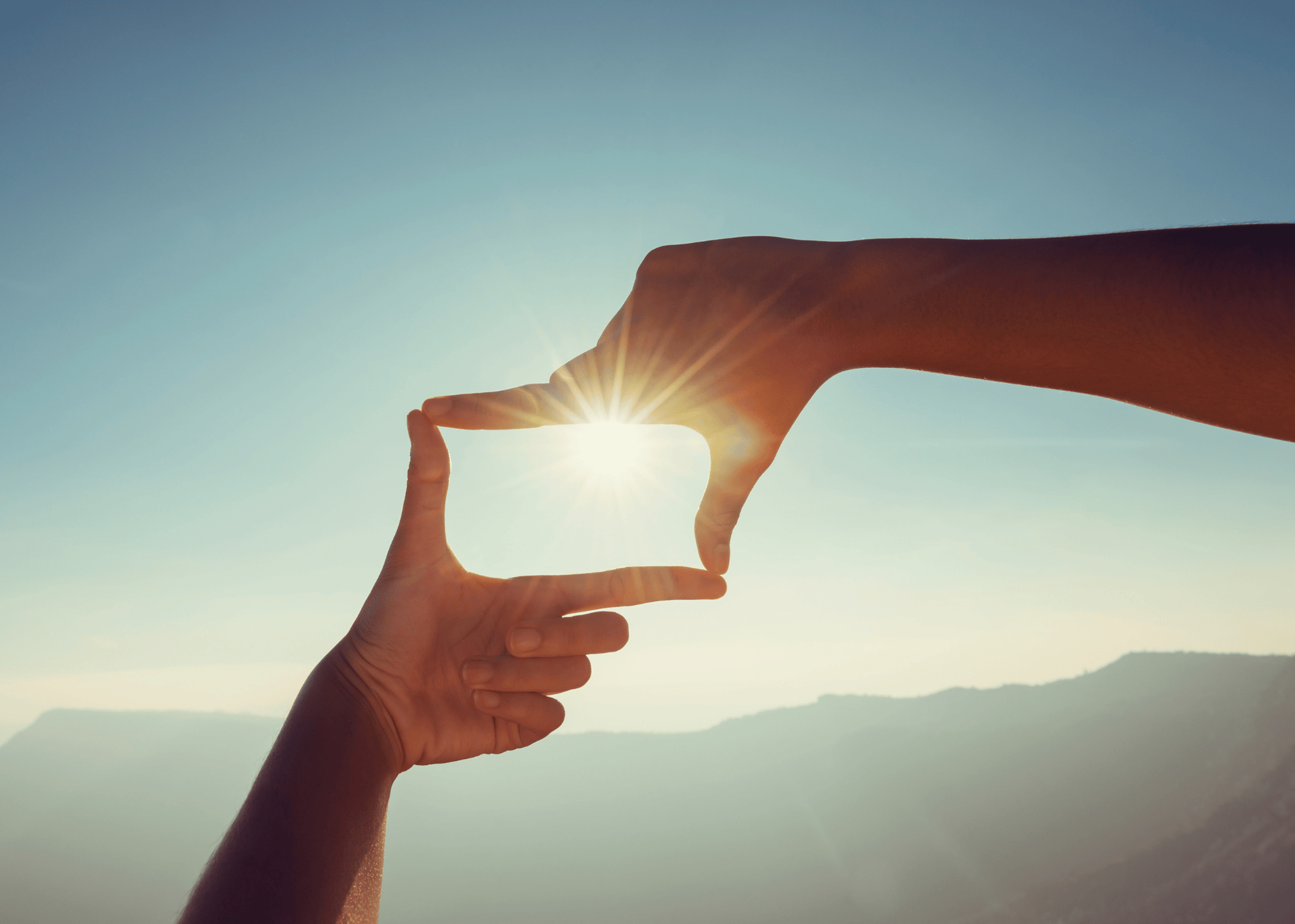 hands with fingers together creating a box shape with sun shining through